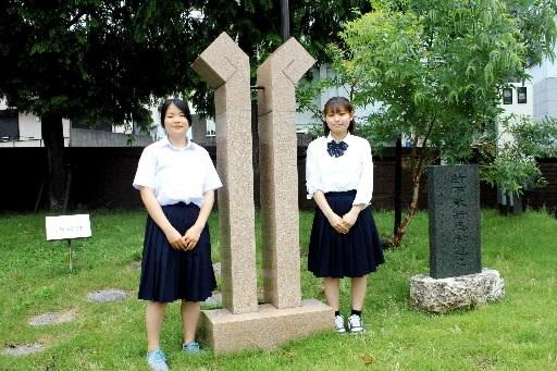 校庭にある島田氏を顕彰する「合掌の碑」の前で受賞を喜ぶ米澤周奈さん（左）と森岡愛弥華さん＝兵庫高校