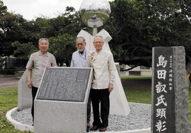 「島田叡氏顕彰碑」の前で俳句大会の発展を誓う実行委員会の（右から）名嘉山興武（なかやまおきたけ）、垣花和、嘉数昇明（かかずのりあき）＝那覇市奥武山町