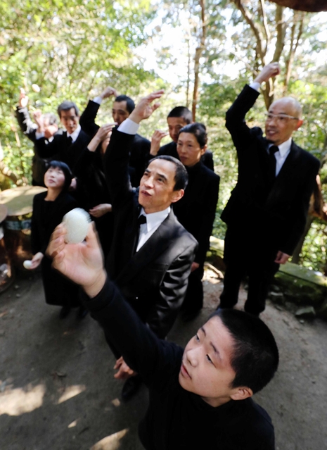 崖の前で一斉におにぎりを放る参拝者＝洲本市上内膳、千光寺（撮影・大山伸一郎）