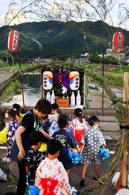 市島の川裾祭り。橋の上の茅の輪をくぐり、ほこらに参拝する＝丹波市市島町市島
