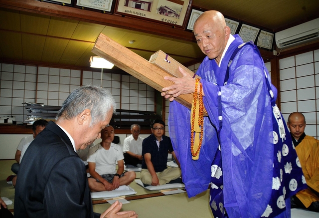 天船地区に伝わる「こっつんさん」。最初に佐藤俊樹住職（右）が、お経の入った木箱で村人の頭を「こっつん」とたたく＝兵庫県多可町八千代区中村