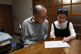 介護サービスも仕事も休みの日曜日。テーブルに着き、介護サービスのスケジュール表を確認する玉垣崇さんと博子さん＝高砂市内