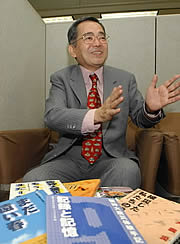 これまで発行した手記集を前に語っていた故高森一徳代表＝２００３年１２月、神戸市内