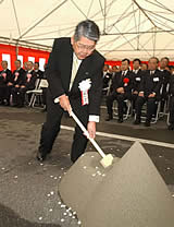 工事の安全を祈り、くわ入れをする稲垣嗣夫神戸新聞社長＝神戸・三宮