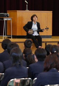 三線を披露するなおちゃん。中学生に震災を語った＝神戸市垂水区星陵台、星陵台中学 