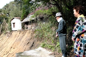 崩れた町道を見つめる山田さん夫妻。つめ跡は今も深い＝１１月１６日、兵庫県津名町興隆寺