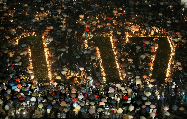 暗闇の中に浮かび上がった「１・１７」。降りしきる雨の中、たくさんの傘の花が灯を包んだ＝１７日午前５時４６分、神戸市中央区、東遊園地 
