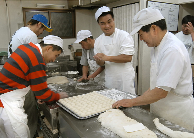 今年の仕事始め。元気にパンをこねる「くららべーかりー」のメンバーたち＝神戸市長田区三番町 