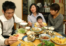 皆、一緒に。実家でベトナム料理を食べるトゥイさん（中央）と康さん（左）＝神戸市須磨区大池町