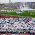 写真上＝復興　式典前演技では大きな未来への架け橋が登場し、花火と歌声がフィナーレを飾った。写真下＝声援　県内のスポーツクラブの子どもたちが、全都道府県の選手団に「ガンバレ」のメッセージを掲げ、熱狂的に迎えた。いずれも神戸市須磨区、ユニバー記念競技場