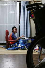 自宅でくつろぎ、寿司（すし）を食べる山本さん。介助者に支えられ、一人暮らしする＝神戸市長田区日吉町２

