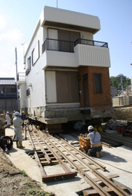 レールで手前側から奥に向かって移転される建物＝淡路市富島