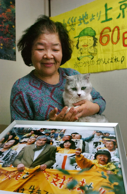デモ　愛猫を抱く切畑輝子さん。小田と先頭を歩いた写真が台所に飾られる＝西宮市薬師町
