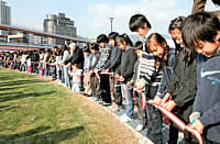 芝生広場を囲んで並び、テープカットする参加者＝神戸市中央区小野浜町（撮影・山口　登）