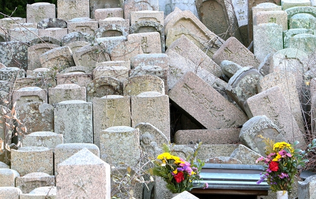 震災で倒れた墓石。人知れず、花が手向けられていた＝淡路市富島