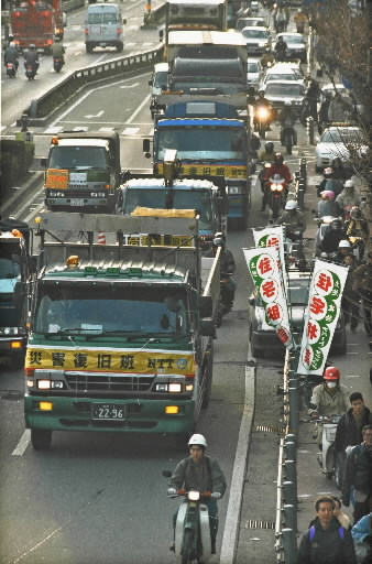 災害復旧のトラックなどで混雑する徳井交差点＝1995年1月19日、神戸市灘区徳井町の国道2号線