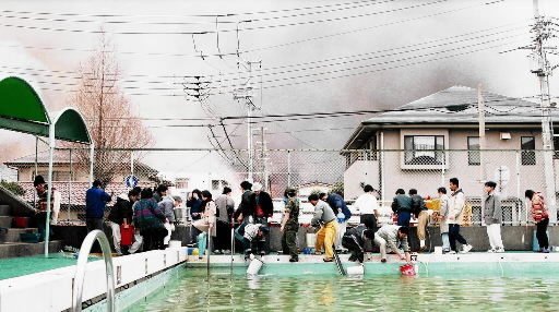 プールの水をバケツリレーし、消火活動する地域の住民＝１９９５年１月１７日、神戸市東灘区御影石町、市立御影小学校