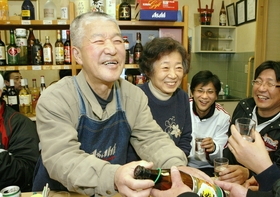 笑顔あふれる店内。常連客との会話を楽しむ前田稔さん（左）、妻の節子さん＝神戸市須磨区千守町１、前田酒店
