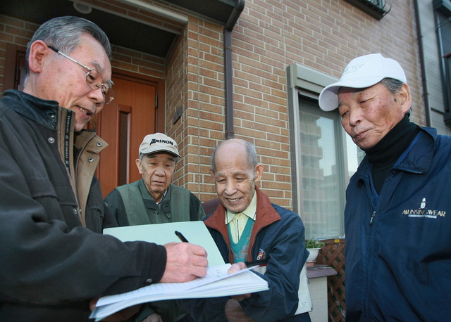 「まずは名簿作りから」。住民に連絡先を記入してもらえるよう呼び掛ける近兼さん（右）ら＝神戸市長田区神楽町６（撮影・神子素慎一）
