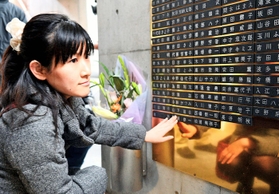 「慰霊と復興のモニュメント」に銘板を張り付ける女性＝２３日、神戸市中央区加納町６（撮影・大山伸一郎）