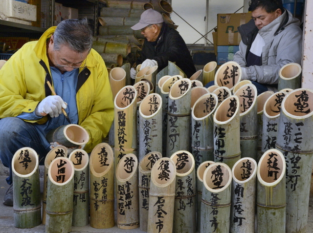 竹灯籠に文字を書き入れる山川泰宏さん（左）＝４日午前、神戸市灘区（撮影・大山伸一郎）