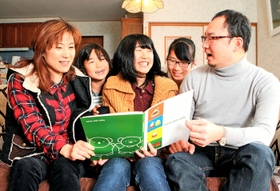 アルバムを開き、歩みを振り返る李唯衣さん（中央）。両親（両端）と、妹の礼衣さん（右から２人目）、亜衣さん（左から２人目）に囲まれて＝神戸市長田区堀切町（撮影・吉田敦史）