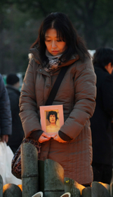 母の写真を手に、竹灯籠を見つめる佐藤悦子さん＝１７日午前７時４分、神戸市中央区加納町６、東遊園地（撮影・中西大二）