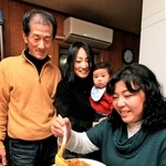 カレーをよそう母の原里美さん（右）。咲人ちゃんを抱く姉の木畑優紀絵さん、父の利昭さんも寄り添う＝１７日夜、神戸市東灘区御影中町７（撮影・峰大二郎）