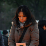 母の写真を手に、竹灯籠を見つめる佐藤悦子さん＝１７日午前７時４分、神戸市中央区加納町６、東遊園地（撮影・中西大二）