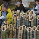 竹灯籠に文字を書き入れる山川泰宏さん（左）＝４日午前、神戸市灘区（撮影・大山伸一郎）