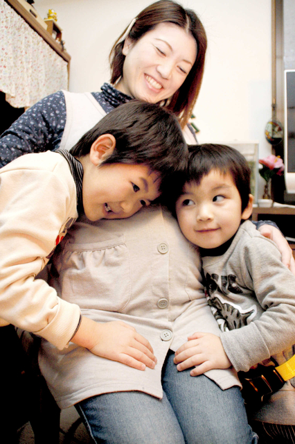 長男出海ちゃん（左）、次男理央ちゃんと一緒に、おなかの中の第３子に話し掛ける富田めぐみさん＝西宮市西波止町