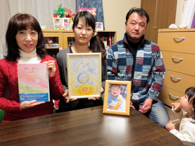 雅人君の写真を前に、完成した絵本とイラストを見せるたかいさん（左）と竹沢さん夫妻＝仙台市若林区