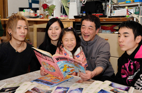 子どもたちと瞳ちゃんのアルバムをめくる竹場満さん（右から２人目）。「めっちゃかわいいやん」という声に思わず笑みがこぼれた＝神戸市灘区千旦通１（撮影・中西幸大）