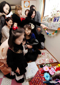 崔秀光さんの遺影の前で語り合う同級生とその子どもたち＝１１日午後、神戸市須磨区千歳町１（撮影・斎藤雅志）