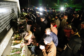 犠牲者の名前を刻んだ碑に献花する人たち＝１７日午前５時４８分、西宮市奥畑、西宮震災記念碑公園