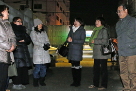 震災で亡くなった藤田依子さんをしのび、自宅跡の空き地前に集まった（右から）父勝彦さん、母君枝さん、妹貴子さんら＝１７日午前６時１６分、神戸市長田区若松町７