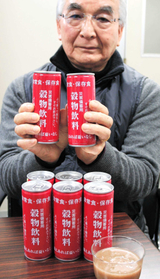 缶入り保存食「三穀食」を手にするミツレフーズの三宅利巨社長＝神戸市中央区海岸通４