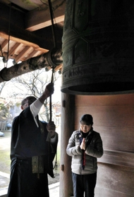 犠牲者を追悼し、鐘を鳴らす国本行信住職（左）と桂子さん＝常隆寺