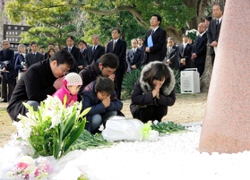 花を手向け手を合わせる岩瀬朗子さん（右）と長男樹弘君（手前中央）ら＝神戸大六甲台キャンパス