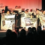 震災直後の新聞紙面を模した衣装で演じる生徒たち＝１１日、東京・国立オリンピック記念青少年総合センター