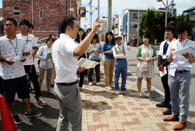 神戸市消防局の職員（中央）から、阪神・淡路大震災当時の状況を聞く学生たち＝神戸市長田区若松町１０