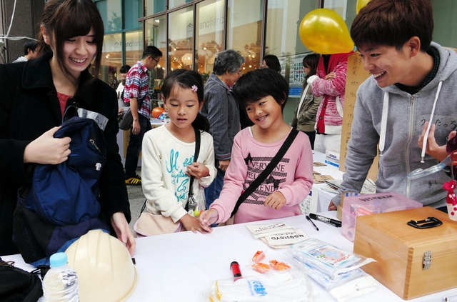 ワークショップに参加した子どもに、非常持ち出し袋の中身を選んでもらう大学生＝神戸市中央区東川崎町１