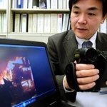 現在は企業誘致推進室で勤務する松崎さん。当時のビデオカメラと映像＝神戸市役所