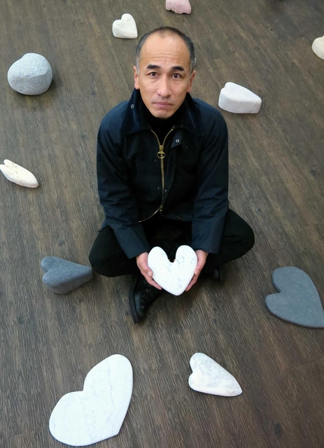 ハートに刻んだ石の作品を並べる彫刻家冨長敦也さん＝神戸市長田区