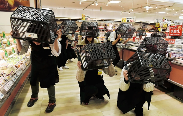 訓練開始と同時に買い物かごを頭にかぶる食料品売り場の従業員ら＝１５日午前、神戸市中央区雲井通６、ダイエー三宮駅前店（撮影・宮路博志）