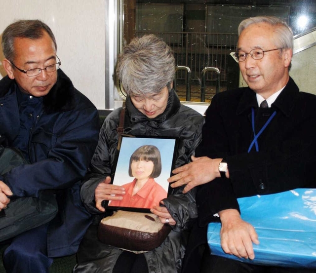 黒田裕子さんの遺影を持ち、臨時便の出発を待つ宇都（うと）幸子さん（中央）、高橋守雄さん（右）ら＝１７日午前４時１２分、神戸市西区糀台５、市営地下鉄西神中央駅