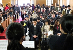 ハンドベルにあわせて黙とうする学生ら＝西宮市上ケ原一番町