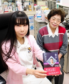 診察室で、完成した本を手にする中條さん（左）と母恵子さん＝大阪府寝屋川市