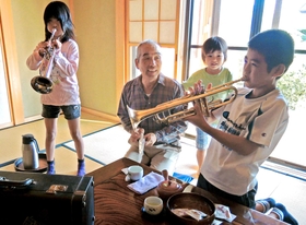 高須恒さんが見守る中、長男厚志さんのトランペットを吹き鳴らす孫たち＝静岡県磐田市気子島