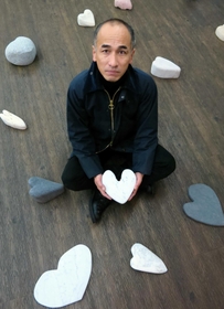 ハートに刻んだ石の作品を並べる彫刻家冨長敦也さん＝神戸市長田区